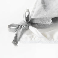 High-resolution close-up of a corner loop on an organic cotton comforter, highlighting the detailed stitching and secure attachment point for duvet covers.